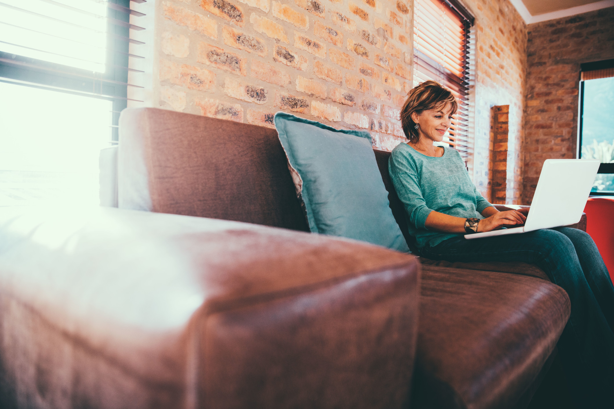 modern-happy-female-adult-sitting-on-couch-writing-e-mail-with-laptop-on-couch-in-modern-homeoffice_t20_6wmNO9